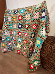 a crocheted blanket sitting on top of a wooden floor next to a basket