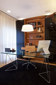 a glass desk with a laptop on it in front of a book shelf filled with books