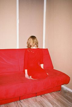 a woman sitting on top of a red couch