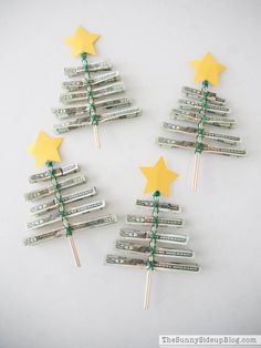 three christmas trees made out of dollar bills with green and yellow stars on them, sitting next to each other