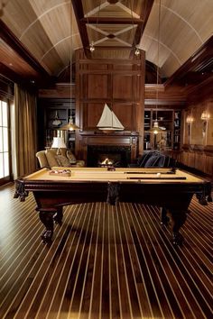 a pool table in the middle of a room with wood paneling on the walls