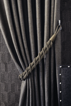 a rope wrapped around the end of a curtain in front of a black and gray background