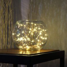 a glass vase filled with lights sitting on top of a table