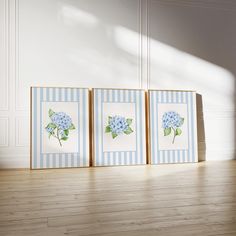 three framed pictures with blue flowers in them on a wooden floor next to a white wall