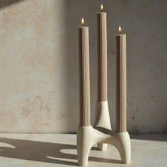 two candles sitting on top of each other in front of a wall with no one around them