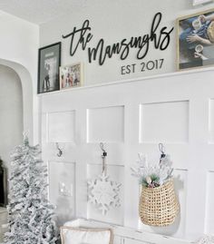 a white christmas tree sitting on top of a wooden table next to a wall mounted sign