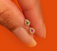 a woman's hand with two different colored stones on her finger and an orange background