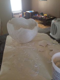 a large white bowl sitting on top of a table next to a can of paint