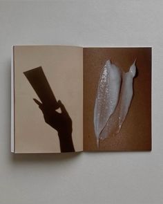 an open book with a shadow of a person holding a piece of paper