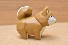 a brown and white dog figurine sitting on top of a wooden table next to a wall