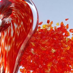 a red and white glass vase sitting on top of a table next to a pile of gummy bears