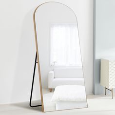 a mirror sitting on top of a white floor next to a bed