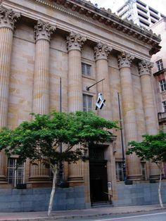 an old building with columns and trees in front