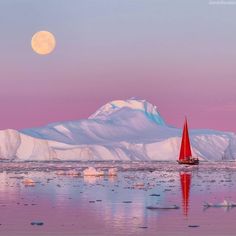 a red sailboat in the water near icebergs