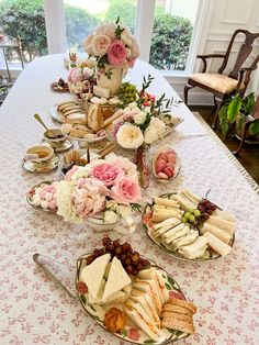 a table topped with plates filled with sandwiches and desserts next to a potted plant