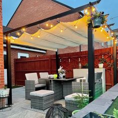 an outdoor dining area with patio furniture and string lights on the pergolated roof