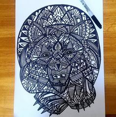 an intricately designed paper cut art piece on a wooden table with marker and pen