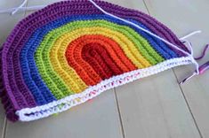 a crocheted potholder with a rainbow design on it, sitting on the floor