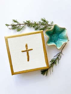 a cross is sitting on top of a card holder next to a green leafy branch