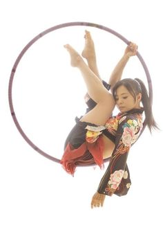 a woman is doing aerial tricks on a hoop