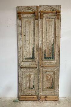 an old pair of wooden doors sitting on top of a white floor next to a wall