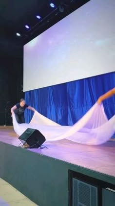 a woman is dancing on a stage with a long white cloth draped over her head