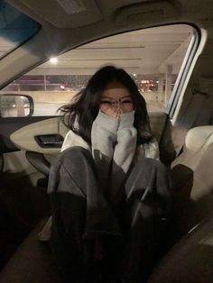 a woman sitting in the back seat of a car with her hand on her face