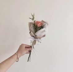 a person holding a bouquet of flowers in one hand and tied with ribbon on the other