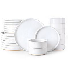 a stack of white plates and cups sitting next to each other on a white surface