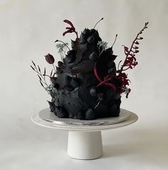 a black cake on a white plate with red flowers