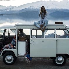 a woman sitting on the roof of a white van