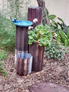 three wooden stumps with plants in them and a birdbath on the top