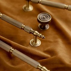 three metal rods are on top of a brown cloth with gold trimmings and knobs