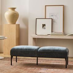 a blue bench sitting on top of a rug next to a table with a vase