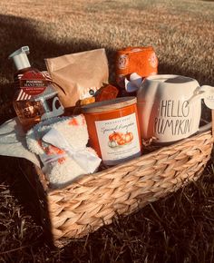 a basket filled with food sitting on top of a grass covered field next to a cup