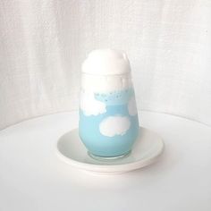 a blue and white vase sitting on top of a white plate with clouds painted on it