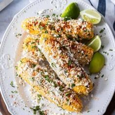 some food is on a white plate with limes and parmesan sprinkles