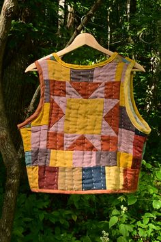 a quilted vest hanging from a tree in the woods