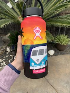 a person holding up a water bottle with an image of a vw bus on it