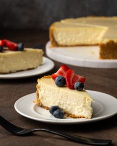 there is a piece of cheesecake with berries on top and a fork next to it