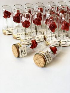 wine corks with red roses in them are lined up on a white table top