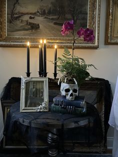 a table topped with books and a skull sitting on top of it next to two candles