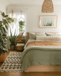 a bedroom with a bed, rug and plants in it