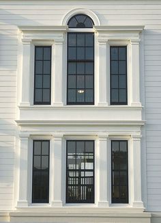 a large white building with two windows and a clock on the side of it's face