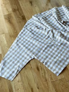 an unbuttoned white and blue checkered shirt laying on the floor next to a pair of scissors