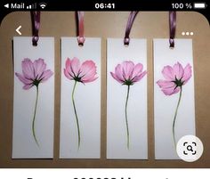 three tags with pink flowers painted on them hanging from a line next to each other