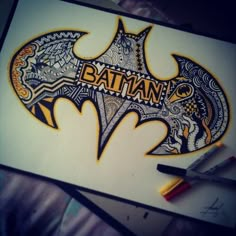 the batman symbol is drawn on paper with markers