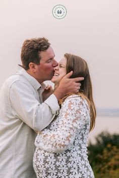 a man and woman kissing in front of the ocean