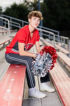 a young man sitting on a bench holding a cheerleader pom - pom