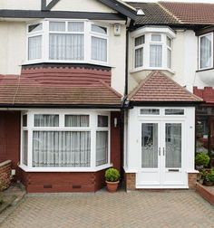 a house with white doors and windows on the outside, brick walkway leading up to it's front door